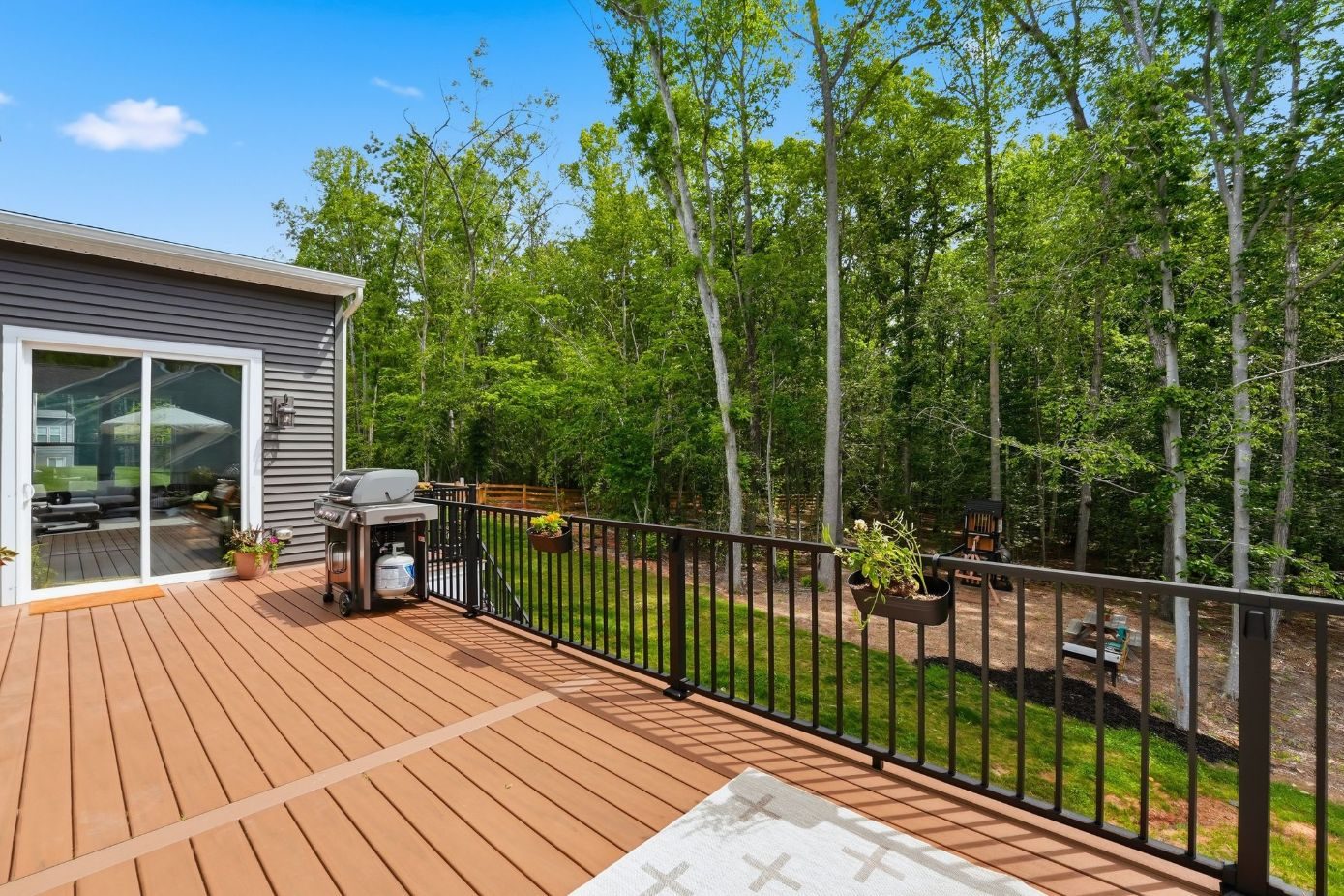 Composite deck with black aluminum railing backing onto woods