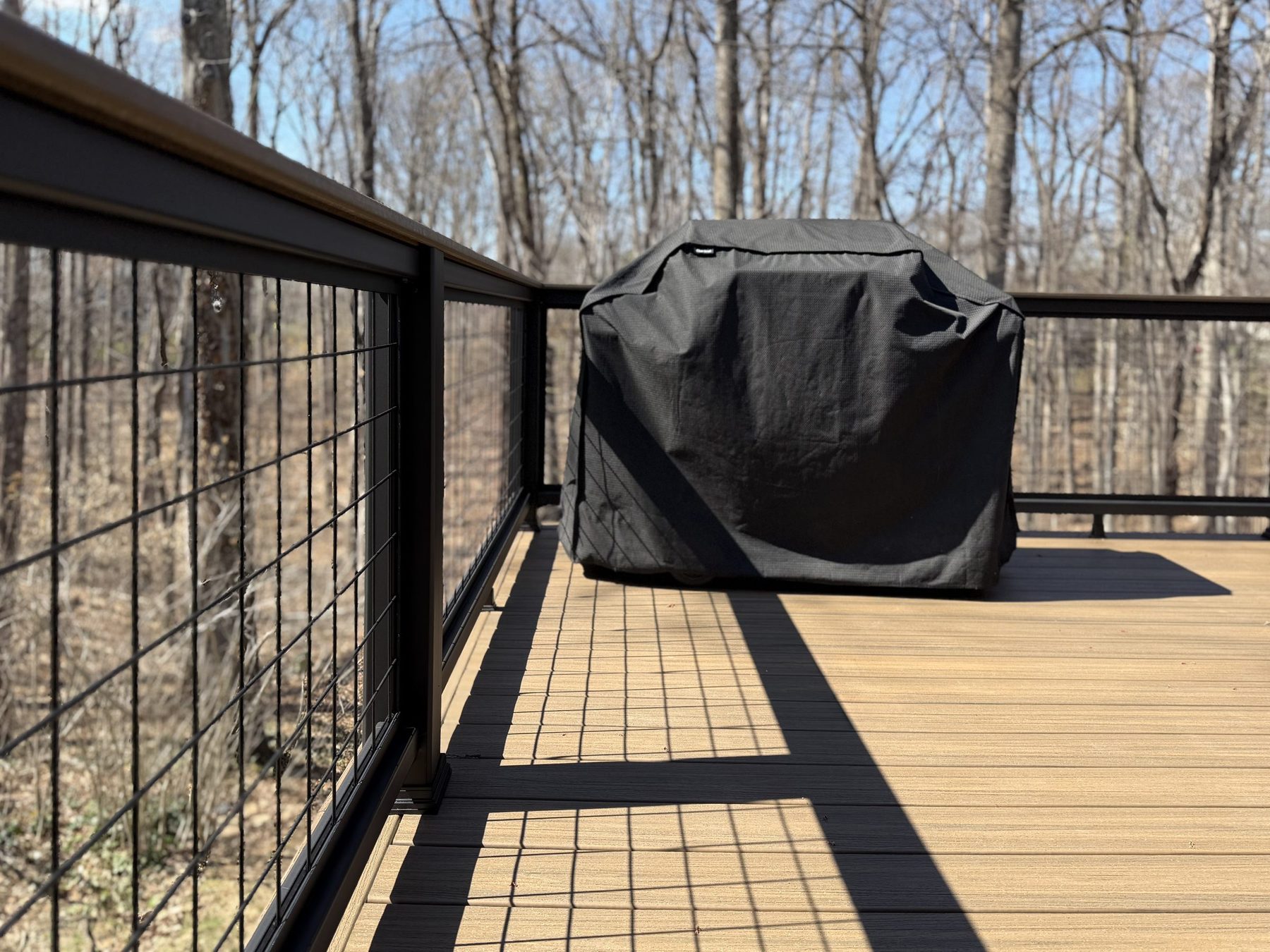 Composite deck with black hog-wire railing overlooking the trees