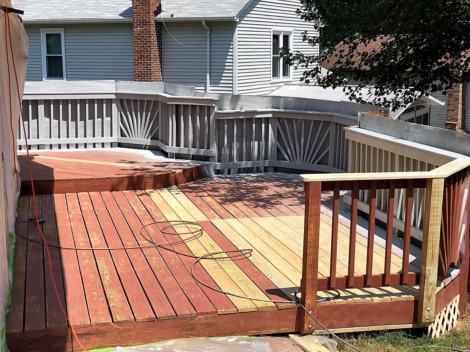 Deck mid-restoration: new pressure-treated boards and a rebuilt railing section going in beside the old stained decking